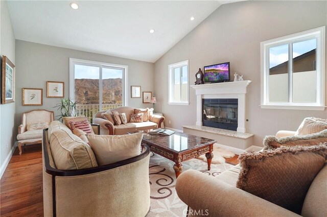 living area featuring wood finished floors, recessed lighting, healthy amount of natural light, a fireplace, and baseboards