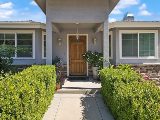entrance to property with stucco siding and a chimney