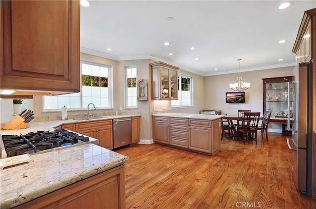 kitchen featuring stainless steel appliances, a sink, light wood-type flooring, a chandelier, and a peninsula