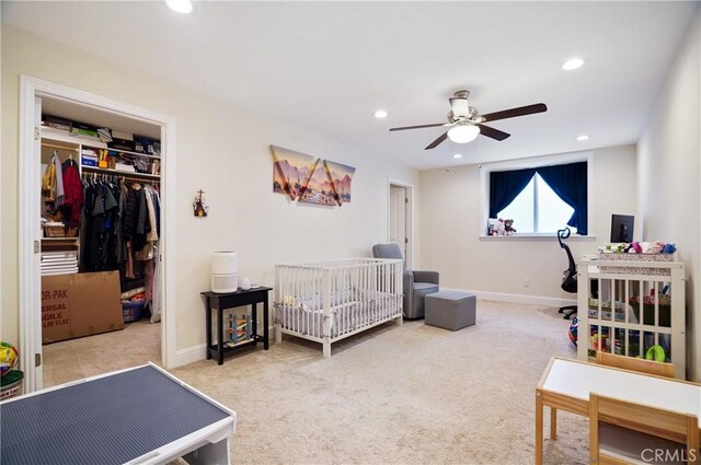 carpeted bedroom featuring recessed lighting, a closet, baseboards, a crib, and a ceiling fan