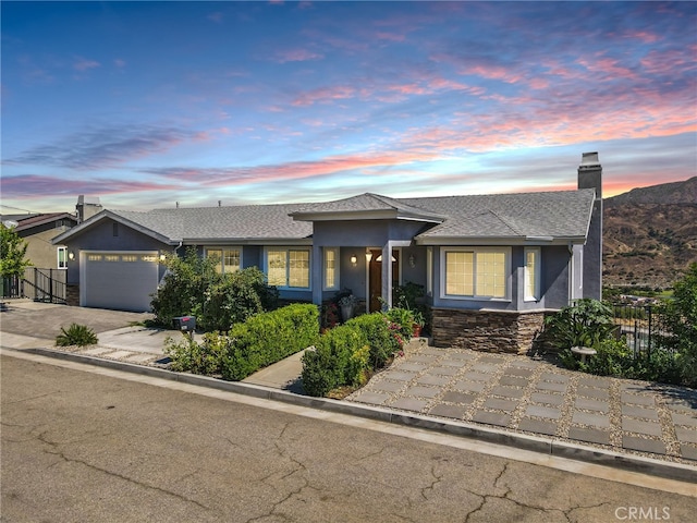 ranch-style house with a chimney, fence, an attached garage, and stucco siding
