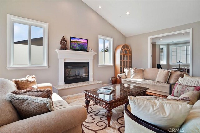 living room featuring recessed lighting, a glass covered fireplace, and lofted ceiling