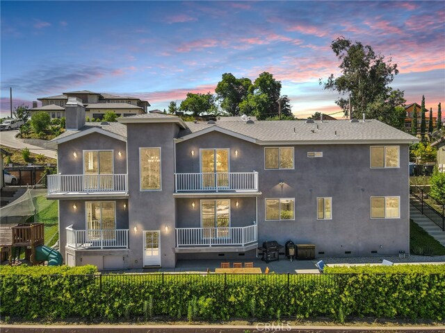 back of property with a balcony, stucco siding, a patio area, and fence