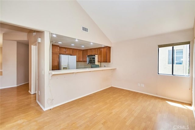 2990 Malaga Cir Unit C, Diamond Bar, CA 91765 - kitchen with white refrigerator with ice dispenser, stainless steel microwave, brown cabinets, light countertops, and high vaulted ceiling