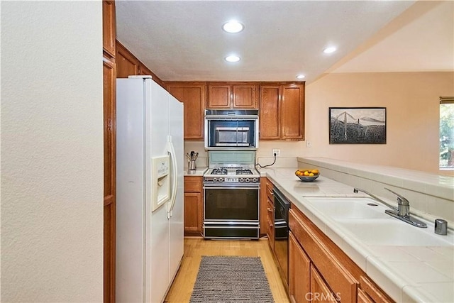 2990 Malaga Cir Unit C, Diamond Bar, CA 91765 - kitchen with white fridge with ice dispenser, range with gas cooktop, a sink, brown cabinetry, and light wood-style floors