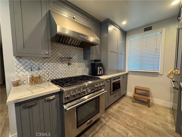 14825 Cranbrook Ave, Hawthorne, CA 90250 - kitchen with stainless steel range, wall chimney exhaust hood, gray cabinets, backsplash, and light stone counters