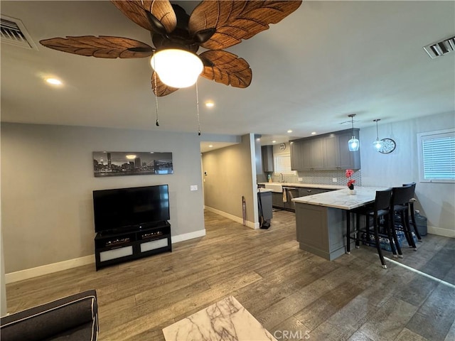 14825 Cranbrook Ave, Hawthorne, CA 90250 - kitchen featuring gray cabinetry, a peninsula, a breakfast bar area, wood finished floors, and recessed lighting