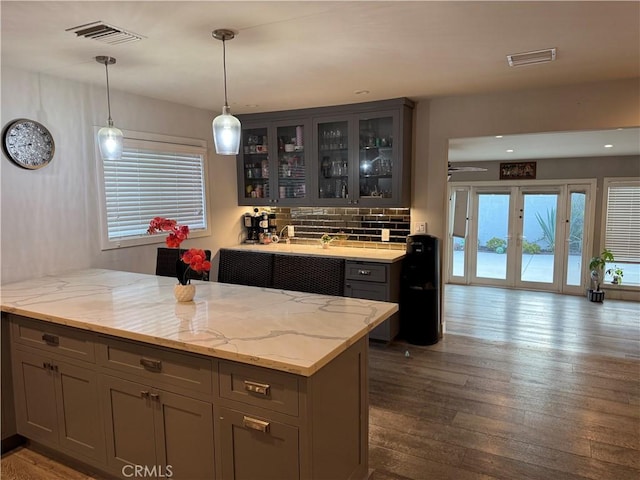 14825 Cranbrook Ave, Hawthorne, CA 90250 - kitchen featuring dark wood-type flooring, a peninsula, decorative backsplash, light stone countertops, and glass insert cabinets