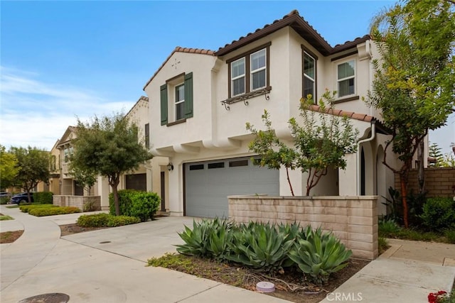 mediterranean / spanish home with a garage, stucco siding, concrete driveway, and a tiled roof
