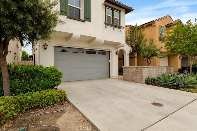 mediterranean / spanish-style house with stucco siding, a garage, concrete driveway, and a tiled roof