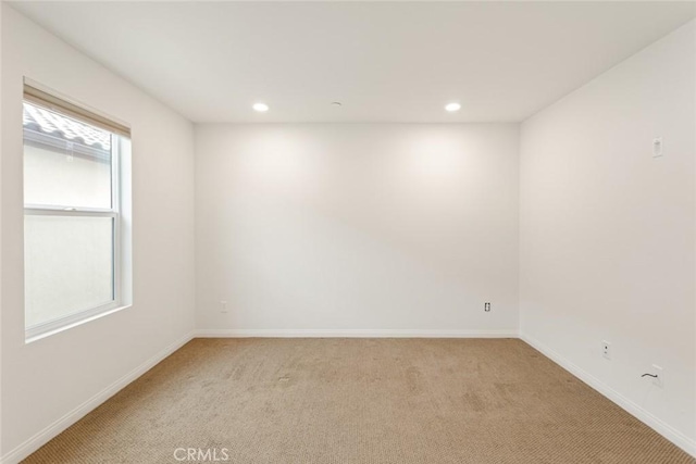 empty room featuring light carpet, recessed lighting, and baseboards