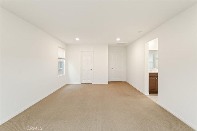 empty room featuring light colored carpet, recessed lighting, and baseboards