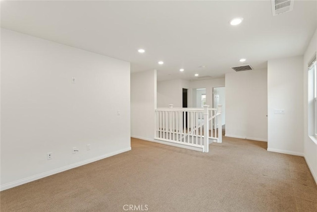 spare room featuring light colored carpet, recessed lighting, and baseboards