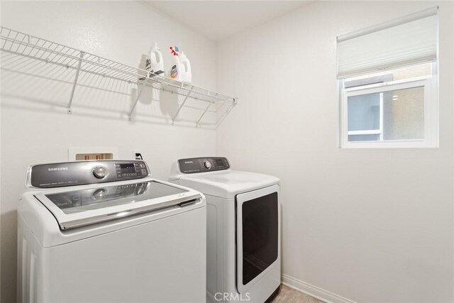 washroom with independent washer and dryer and baseboards