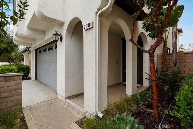 view of exterior entry featuring stucco siding and a garage