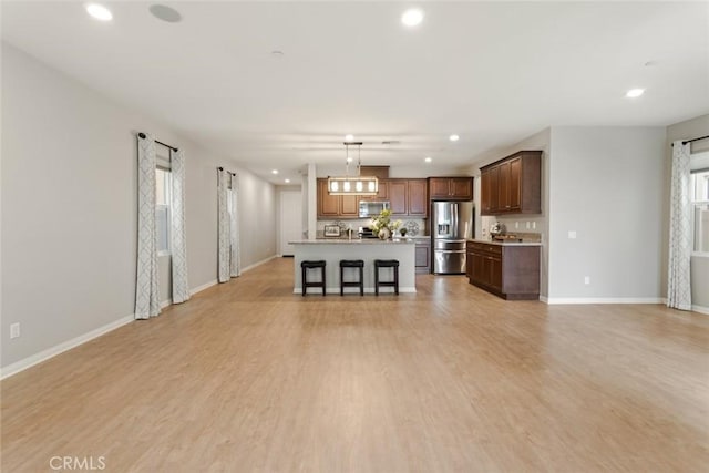 unfurnished living room featuring recessed lighting, light wood finished floors, and baseboards