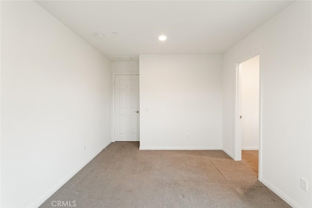 empty room featuring light colored carpet, baseboards, recessed lighting, and a smoke detector