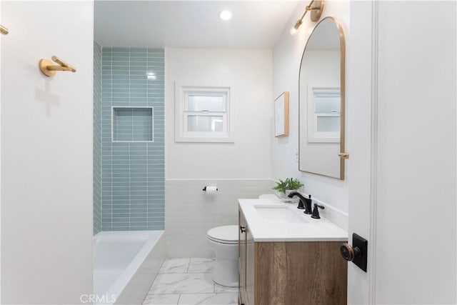 full bath featuring toilet, vanity, marble finish flooring, and tile walls