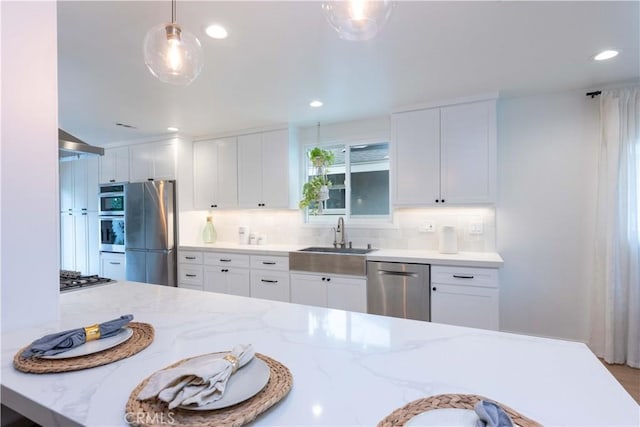 kitchen featuring appliances with stainless steel finishes, a sink, backsplash, white cabinets, and recessed lighting
