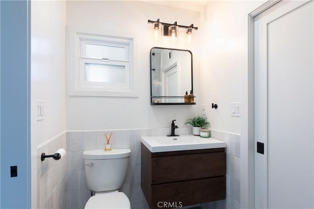 bathroom with tile walls, toilet, vanity, and wainscoting