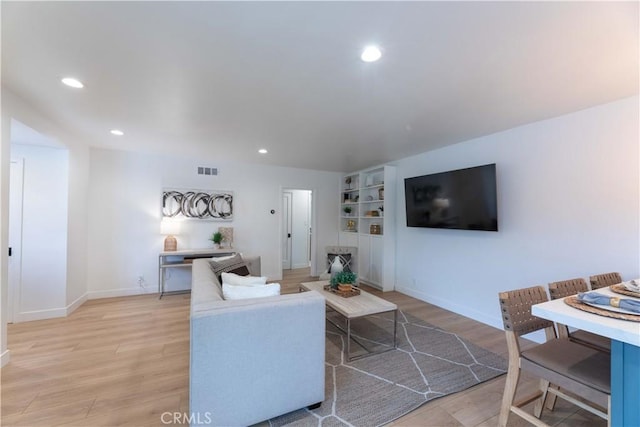 living area with light wood-style flooring, recessed lighting, baseboards, and built in features