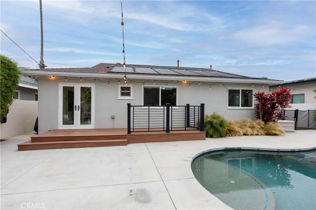 rear view of house featuring french doors, stucco siding, a wooden deck, and fence
