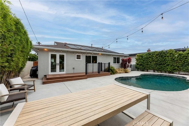 view of swimming pool featuring french doors, a deck, a fenced backyard, and a patio