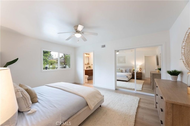 bedroom featuring light wood finished floors, a closet, a ceiling fan, and ensuite bathroom