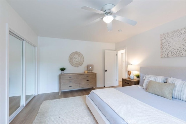 bedroom featuring wood finished floors, baseboards, ceiling fan, and a closet