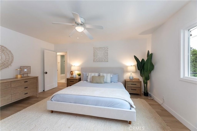 bedroom featuring multiple windows, light wood-style flooring, a ceiling fan, and baseboards