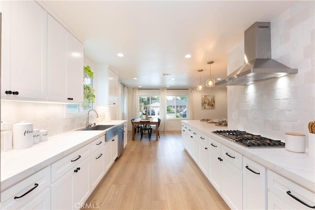kitchen featuring exhaust hood, appliances with stainless steel finishes, white cabinetry, light wood finished floors, and recessed lighting