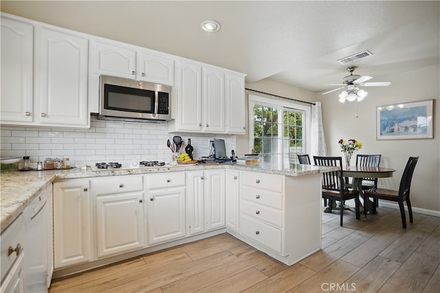 11806 Thunderbird Ave, Porter Ranch, CA 91326 - kitchen with stainless steel microwave, white gas cooktop, backsplash, white cabinets, and light wood-style flooring