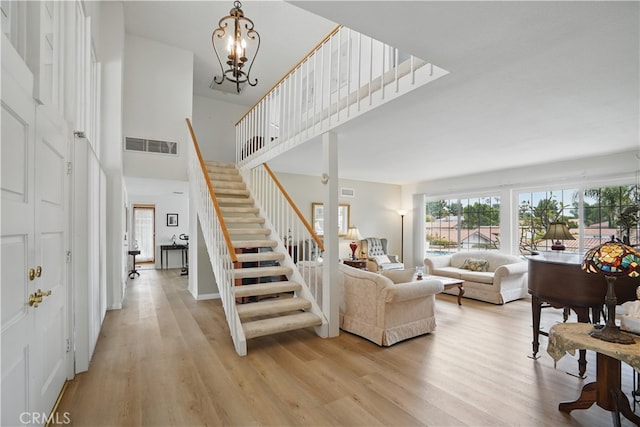 11806 Thunderbird Ave, Porter Ranch, CA 91326 - living area featuring stairs, healthy amount of natural light, light wood-style flooring, a high ceiling, and a chandelier