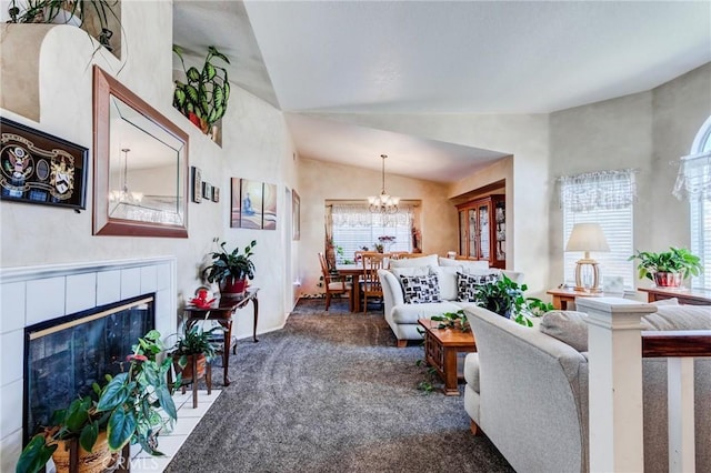 living area with a tiled fireplace, a chandelier, vaulted ceiling, and carpet flooring