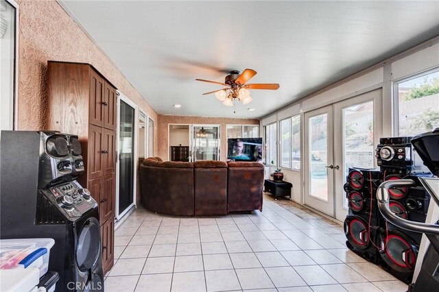 living area with light tile patterned flooring, a ceiling fan, and french doors
