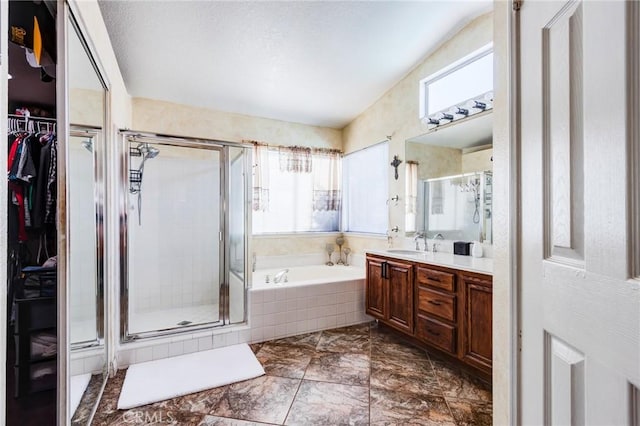 full bathroom featuring a stall shower, vanity, a bath, and a spacious closet