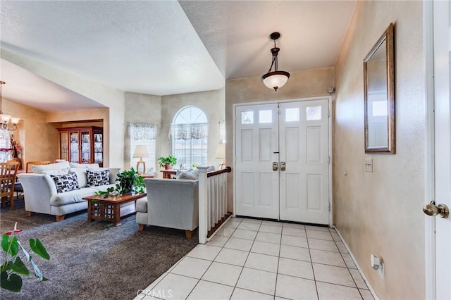 entryway featuring healthy amount of natural light, light tile patterned floors, a chandelier, light colored carpet, and a textured ceiling