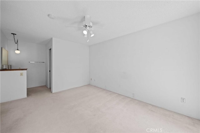 empty room with carpet flooring, ceiling fan, and a textured ceiling