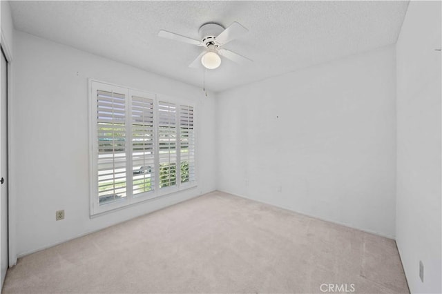 carpeted empty room featuring ceiling fan and a textured ceiling