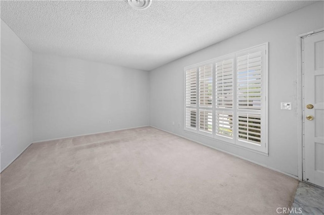 spare room featuring carpet floors, a textured ceiling, and baseboards
