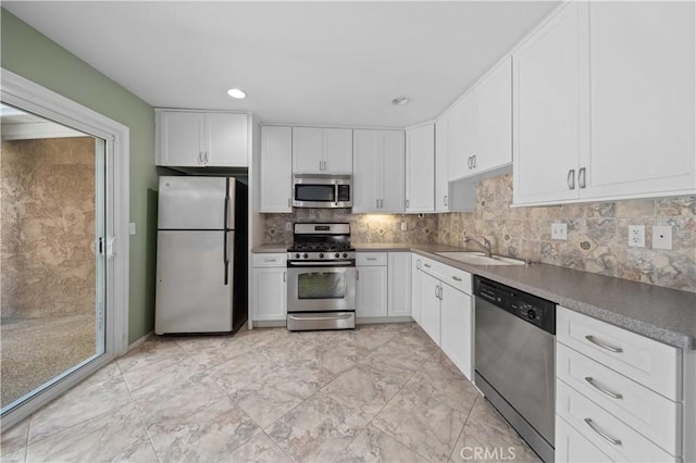 kitchen with appliances with stainless steel finishes, a sink, white cabinets, backsplash, and recessed lighting