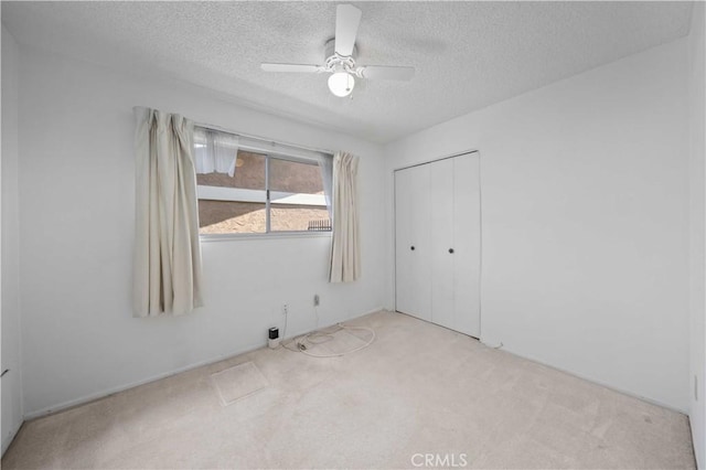 unfurnished bedroom with carpet flooring, a textured ceiling, a closet, and a ceiling fan