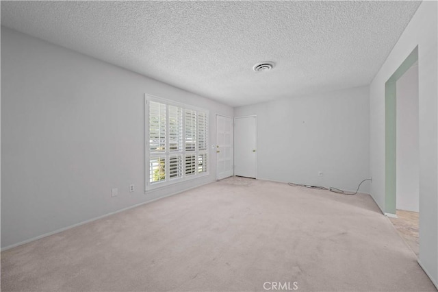 empty room featuring light carpet and a textured ceiling