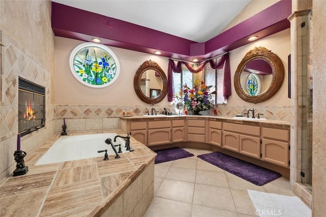 bathroom with a fireplace, tile patterned floors, vaulted ceiling, a garden tub, and double vanity
