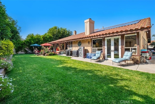 31271 Via Fajita, San Juan Capistrano, CA 92675 - rear view of house featuring french doors, a chimney, a patio area, roof mounted solar panels, and a lawn