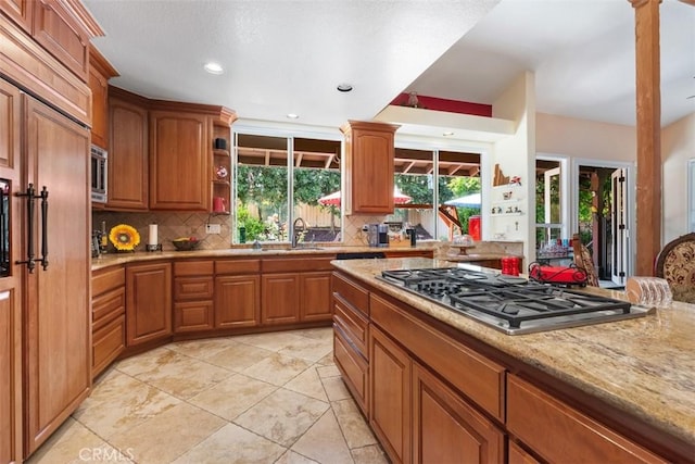 31271 Via Fajita, San Juan Capistrano, CA 92675 - kitchen featuring stainless steel appliances, decorative backsplash, brown cabinetry, open shelves, and light stone counters