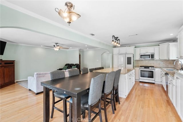6911 E 10th St, Long Beach, CA 90815 - dining area featuring light wood finished floors, ornamental molding, ceiling fan, arched walkways, and recessed lighting