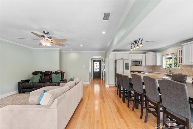 6911 E 10th St, Long Beach, CA 90815 - living room featuring arched walkways, baseboards, recessed lighting, a ceiling fan, and ornamental molding