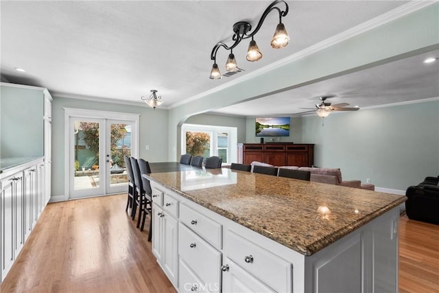 6911 E 10th St, Long Beach, CA 90815 - kitchen featuring a center island, open floor plan, arched walkways, light wood-style floors, and dark stone counters