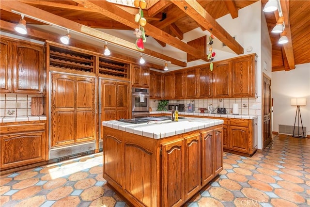 kitchen with tile counters, a center island with sink, tasteful backsplash, and wooden ceiling